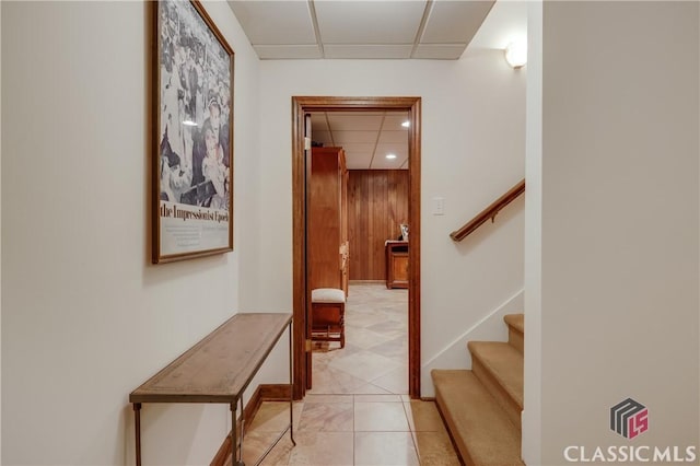 staircase featuring tile patterned floors, wooden walls, and a drop ceiling