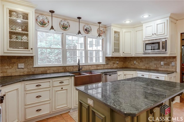 kitchen featuring light tile patterned floors, stainless steel appliances, a center island, tasteful backsplash, and decorative light fixtures