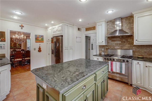 kitchen with wall chimney range hood, stainless steel appliances, green cabinetry, and a kitchen island