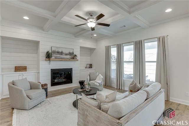 living room with visible vents, light wood-style floors, coffered ceiling, a ceiling fan, and crown molding
