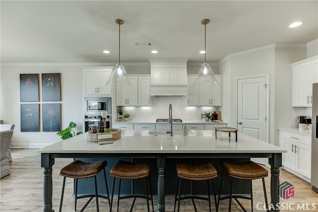 kitchen with stainless steel appliances, a kitchen breakfast bar, a sink, white cabinetry, and light countertops