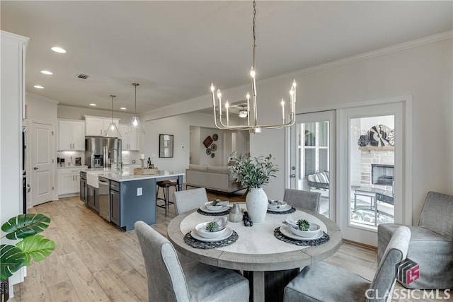 dining space with crown molding, a chandelier, and light hardwood / wood-style floors