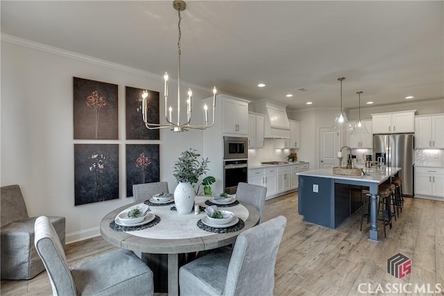 dining room featuring an inviting chandelier, sink, light hardwood / wood-style flooring, and ornamental molding