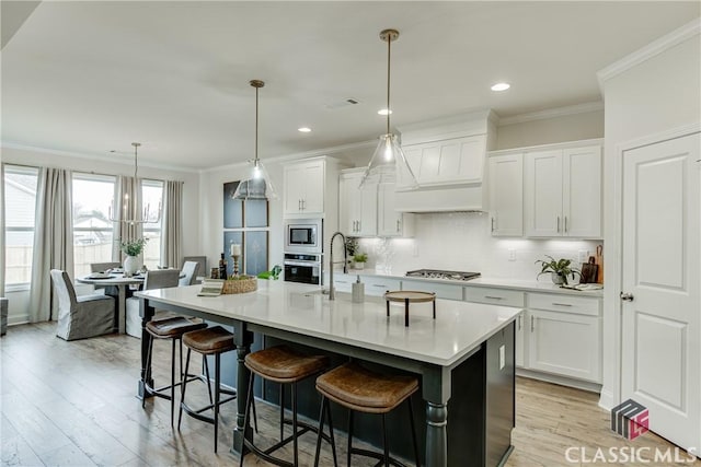 kitchen with pendant lighting, white cabinetry, a kitchen island with sink, stainless steel appliances, and decorative backsplash