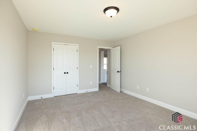 unfurnished bedroom with light colored carpet and a closet