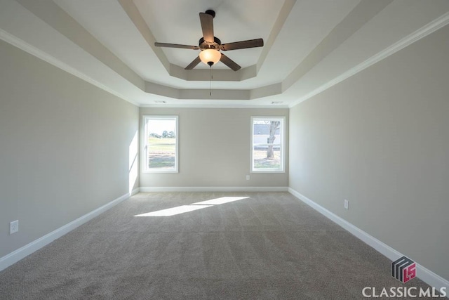 carpeted empty room featuring a raised ceiling, crown molding, and ceiling fan