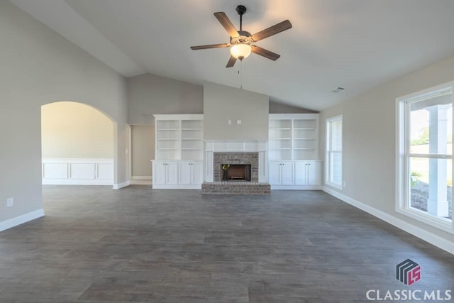 unfurnished living room with dark wood-type flooring, built in features, ceiling fan, a brick fireplace, and vaulted ceiling