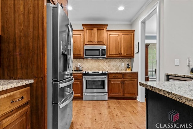 1750 Ryland Hills Dr, Watkinsville, GA 30677 - kitchen featuring ornamental molding, brown cabinetry, stainless steel appliances, backsplash, and light wood-style flooring