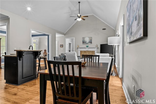 1750 Ryland Hills Dr, Watkinsville, GA 30677 - dining room with vaulted ceiling, a tiled fireplace, visible vents, ceiling fan, and light wood finished floors