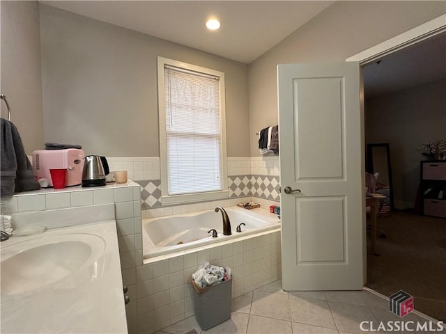 bathroom featuring a relaxing tiled tub, lofted ceiling, tile patterned floors, and sink