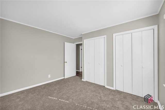 unfurnished bedroom with two closets, crown molding, and carpet flooring