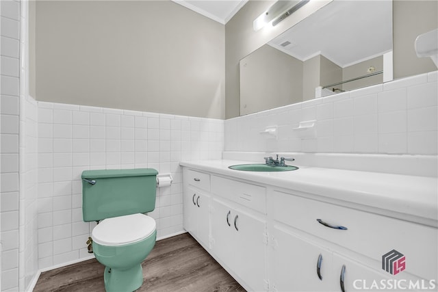 bathroom featuring tile walls, hardwood / wood-style floors, vanity, ornamental molding, and toilet