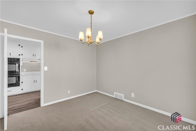 empty room featuring an inviting chandelier, ornamental molding, and carpet flooring