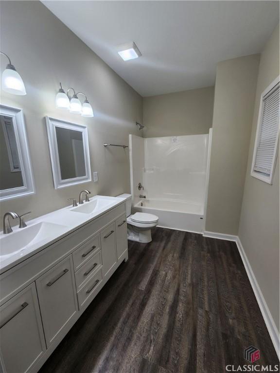 full bathroom featuring hardwood / wood-style flooring, washtub / shower combination, vanity, and toilet