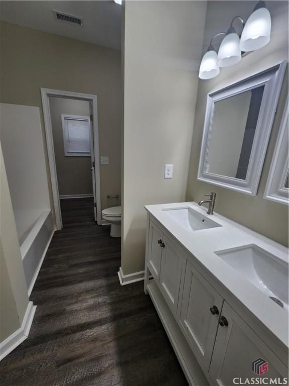 bathroom with hardwood / wood-style flooring, vanity, and toilet