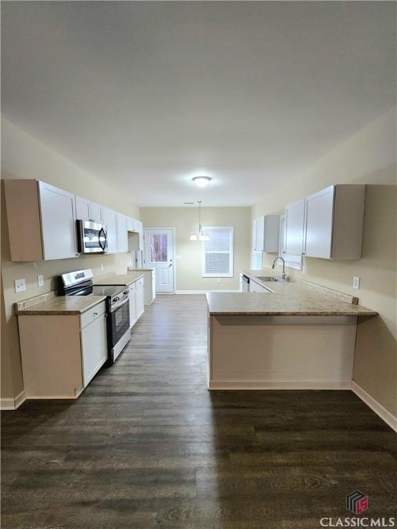 kitchen with sink, white cabinetry, appliances with stainless steel finishes, kitchen peninsula, and pendant lighting