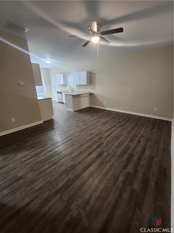 unfurnished living room with ceiling fan, dark hardwood / wood-style flooring, and sink