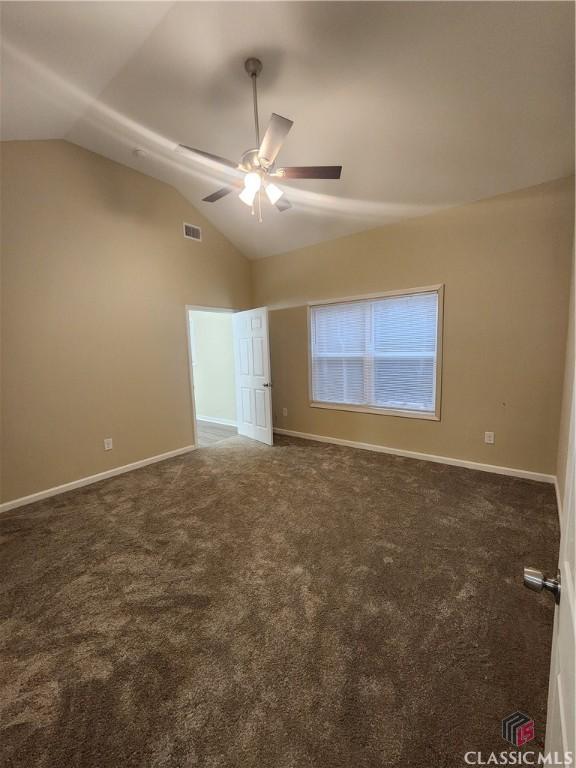 unfurnished bedroom featuring dark colored carpet, lofted ceiling, and ceiling fan