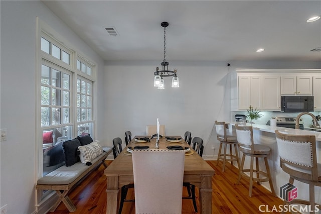 dining area with dark wood-type flooring and a chandelier