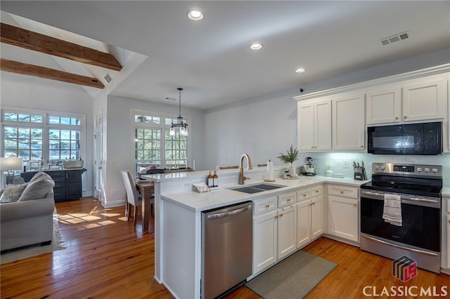 kitchen with stainless steel appliances, kitchen peninsula, sink, and white cabinets