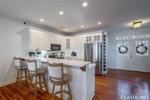 kitchen with white cabinetry, appliances with stainless steel finishes, a kitchen breakfast bar, and kitchen peninsula