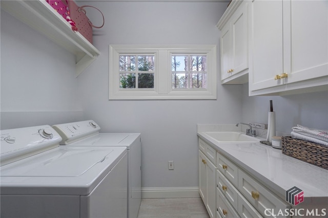 clothes washing area with sink, washer and clothes dryer, and cabinets