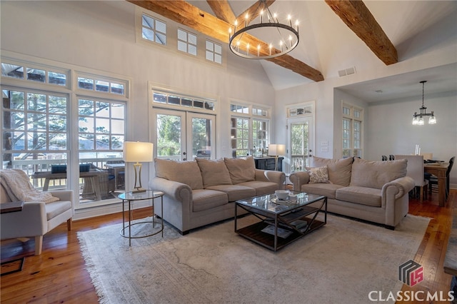 living room with an inviting chandelier, light hardwood / wood-style flooring, french doors, and beamed ceiling