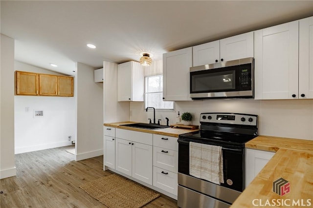 kitchen featuring wood counters, sink, stainless steel appliances, and white cabinets