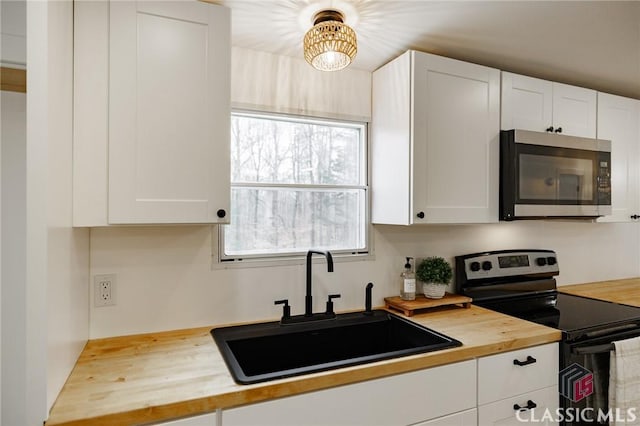 kitchen featuring white cabinets, wooden counters, sink, and electric range