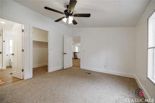 unfurnished bedroom featuring ceiling fan, lofted ceiling, a spacious closet, and carpet