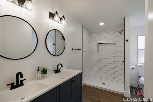 bathroom with vanity, hardwood / wood-style floors, toilet, and tiled shower