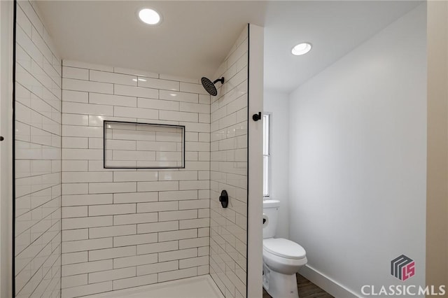 bathroom featuring tiled shower and toilet