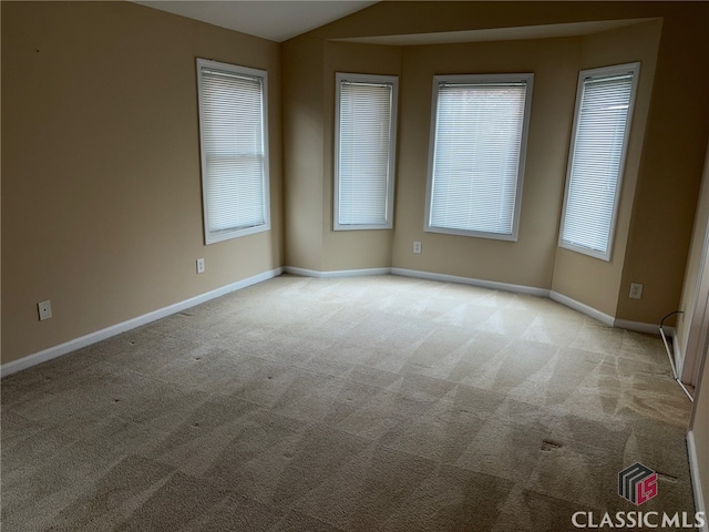 carpeted empty room featuring vaulted ceiling