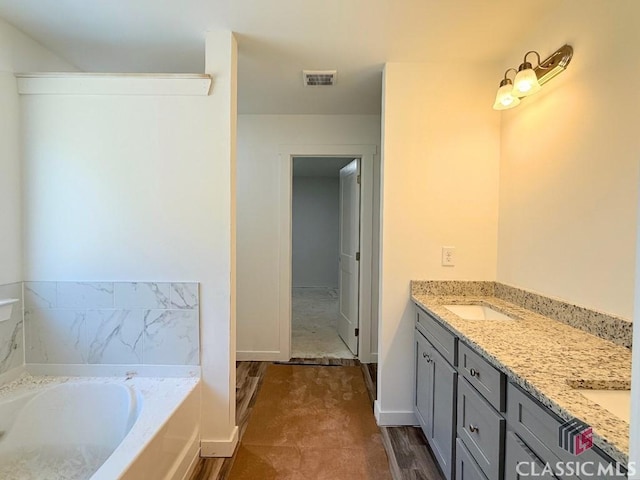 full bath featuring baseboards, visible vents, double vanity, a sink, and a bath