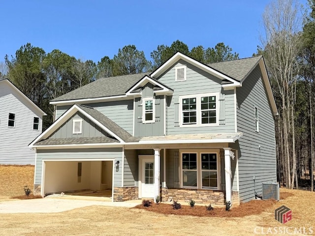 craftsman-style home with stone siding, driveway, board and batten siding, and central AC unit