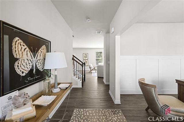 corridor with a wainscoted wall, visible vents, wood finished floors, stairway, and a decorative wall