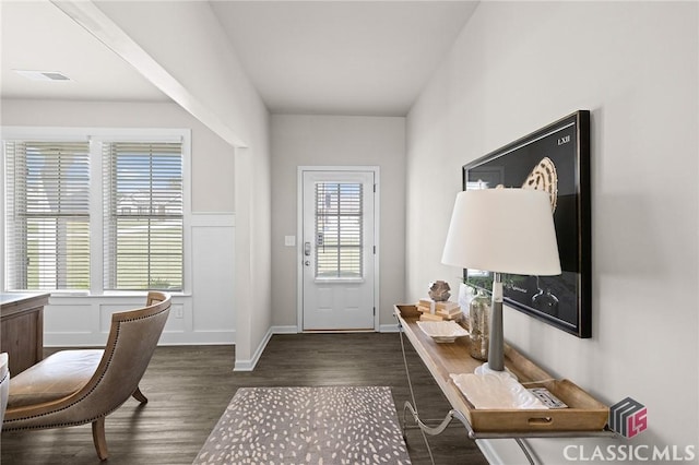 foyer entrance with visible vents, dark wood-style flooring, and a decorative wall