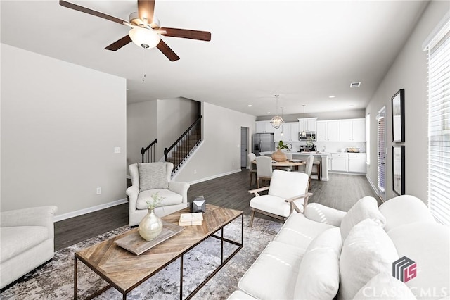 living room with dark wood-type flooring, stairway, and baseboards