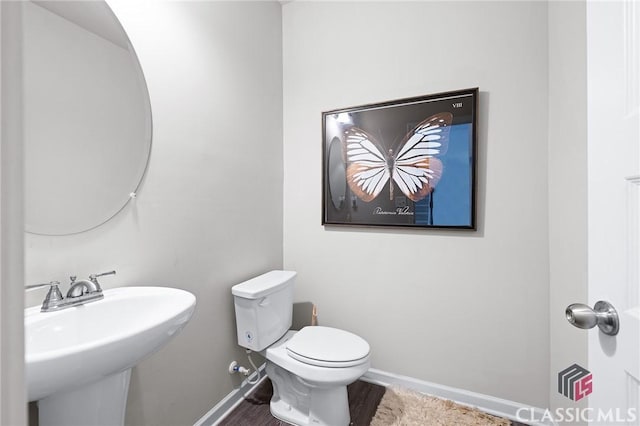 bathroom featuring toilet, baseboards, and a sink