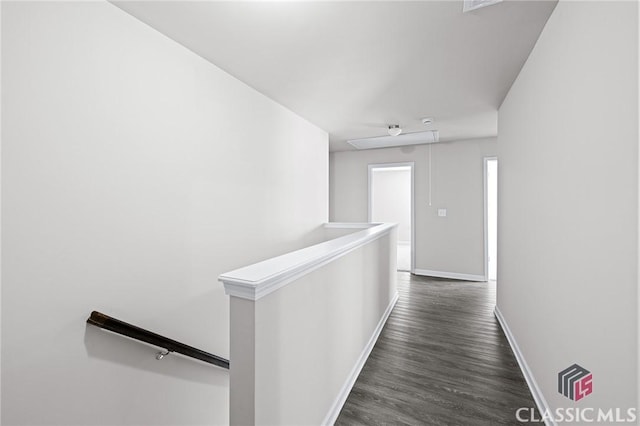 corridor with baseboards, an upstairs landing, attic access, and dark wood finished floors