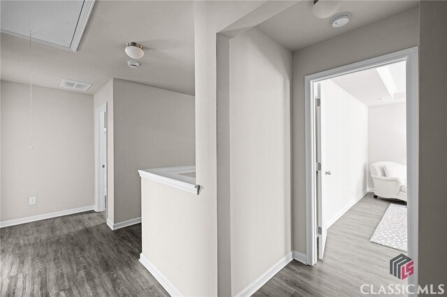 hallway featuring attic access, baseboards, dark wood-style flooring, and visible vents