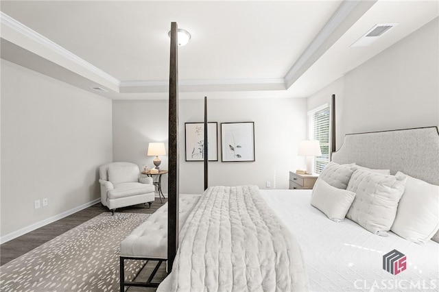 bedroom featuring a tray ceiling, wood finished floors, visible vents, and ornamental molding