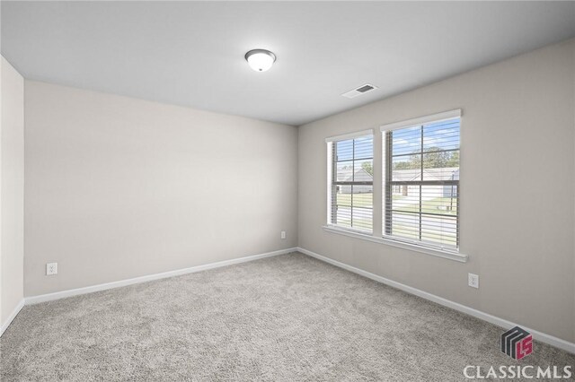 carpeted spare room with visible vents and baseboards