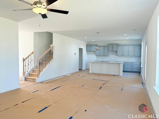 kitchen with light countertops, recessed lighting, ceiling fan with notable chandelier, and baseboards