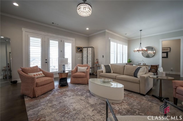 living room with dark wood-type flooring, ornamental molding, and an inviting chandelier