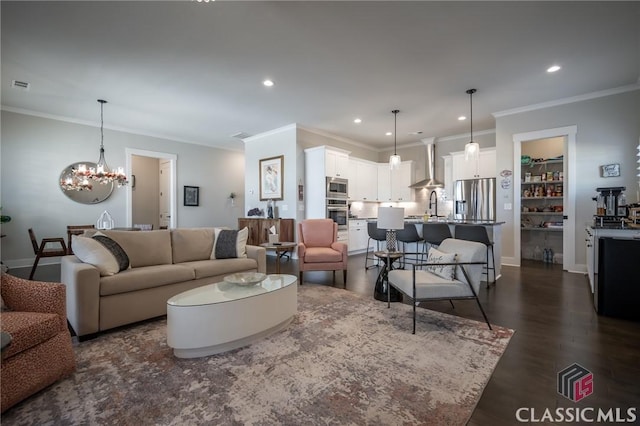 living room featuring dark hardwood / wood-style flooring, sink, ornamental molding, and a chandelier