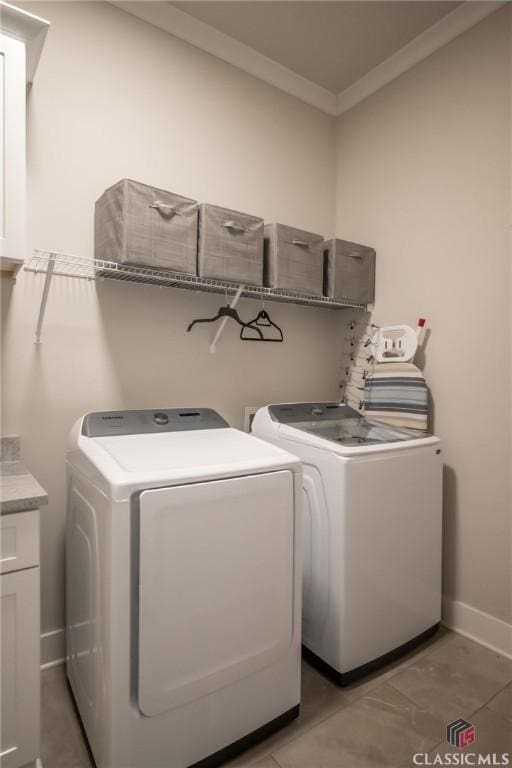 washroom featuring crown molding, cabinets, and washer and clothes dryer