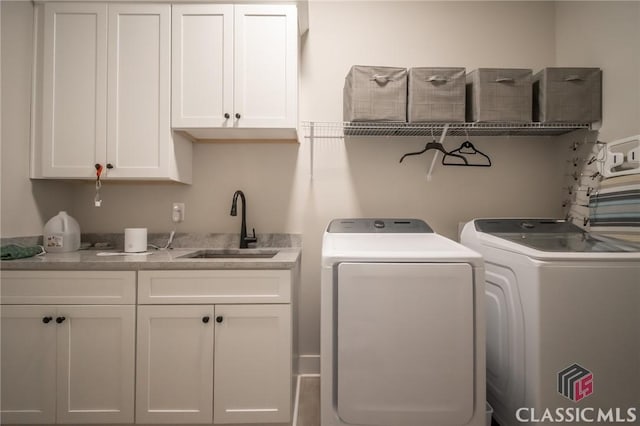 laundry room featuring sink, washer and clothes dryer, and cabinets