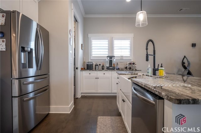 kitchen with pendant lighting, dark stone countertops, white cabinets, stainless steel appliances, and crown molding