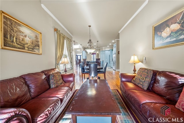 living room featuring hardwood / wood-style flooring, crown molding, and a chandelier